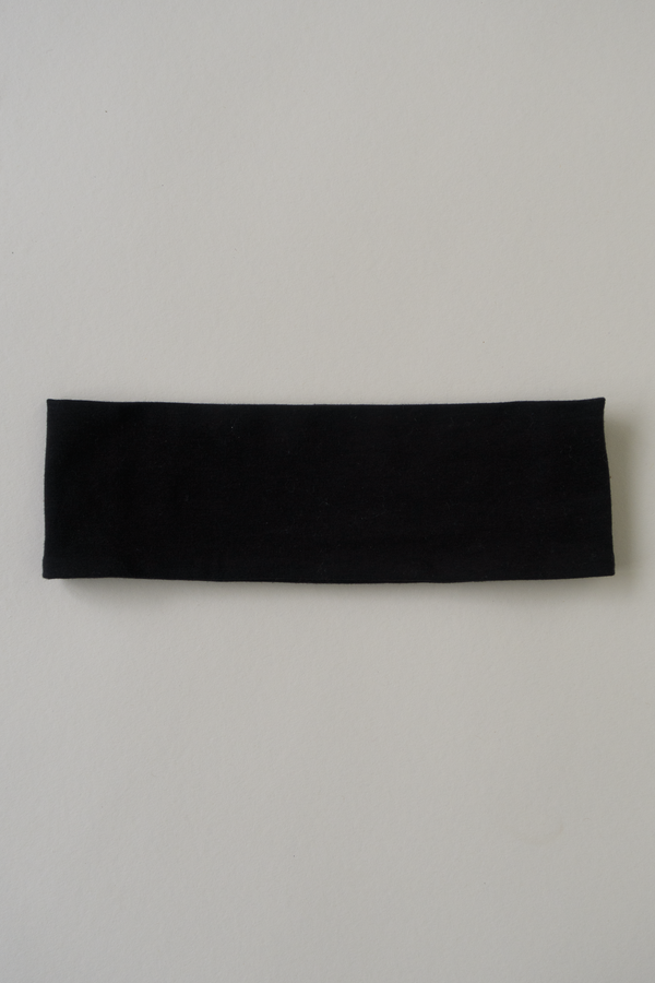 black cotton headband laying on a beige surface 