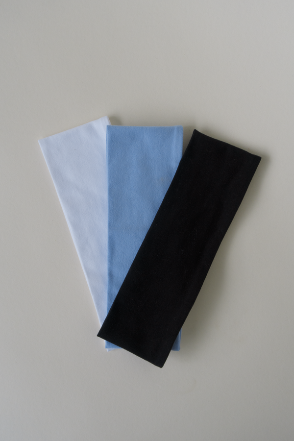 3 cotton headbands laying on a beige surface, black, blue and white