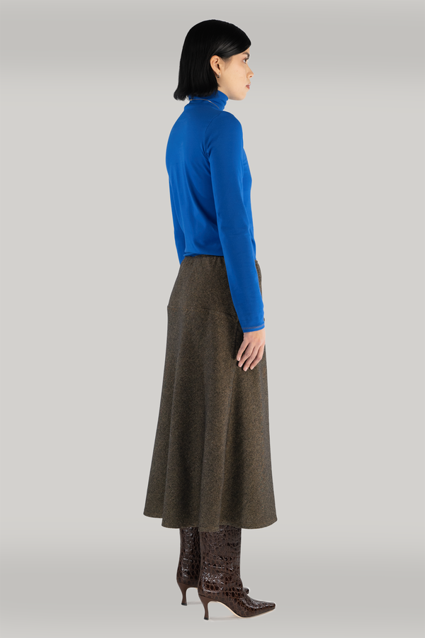 woman standing with long-sleeve cobalt blue turtleneck and long maxi brown wool skirt styled with maroon boots